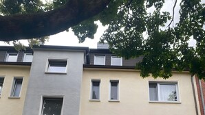 Ein mehrstöckiges Wohngebäude mit flacher Fassade, mehreren Fenstern und einer Tür mit Glasfenster.