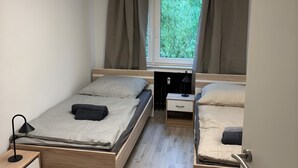 Ein gemütliches Schlafzimmer mit zwei Betten, einem Schreibtisch und einem Fenster mit Vorhängen.