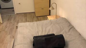 Ein Zimmer mit einem Bett, einem Holzschrank, einer Waschmaschine und einer Lampe.