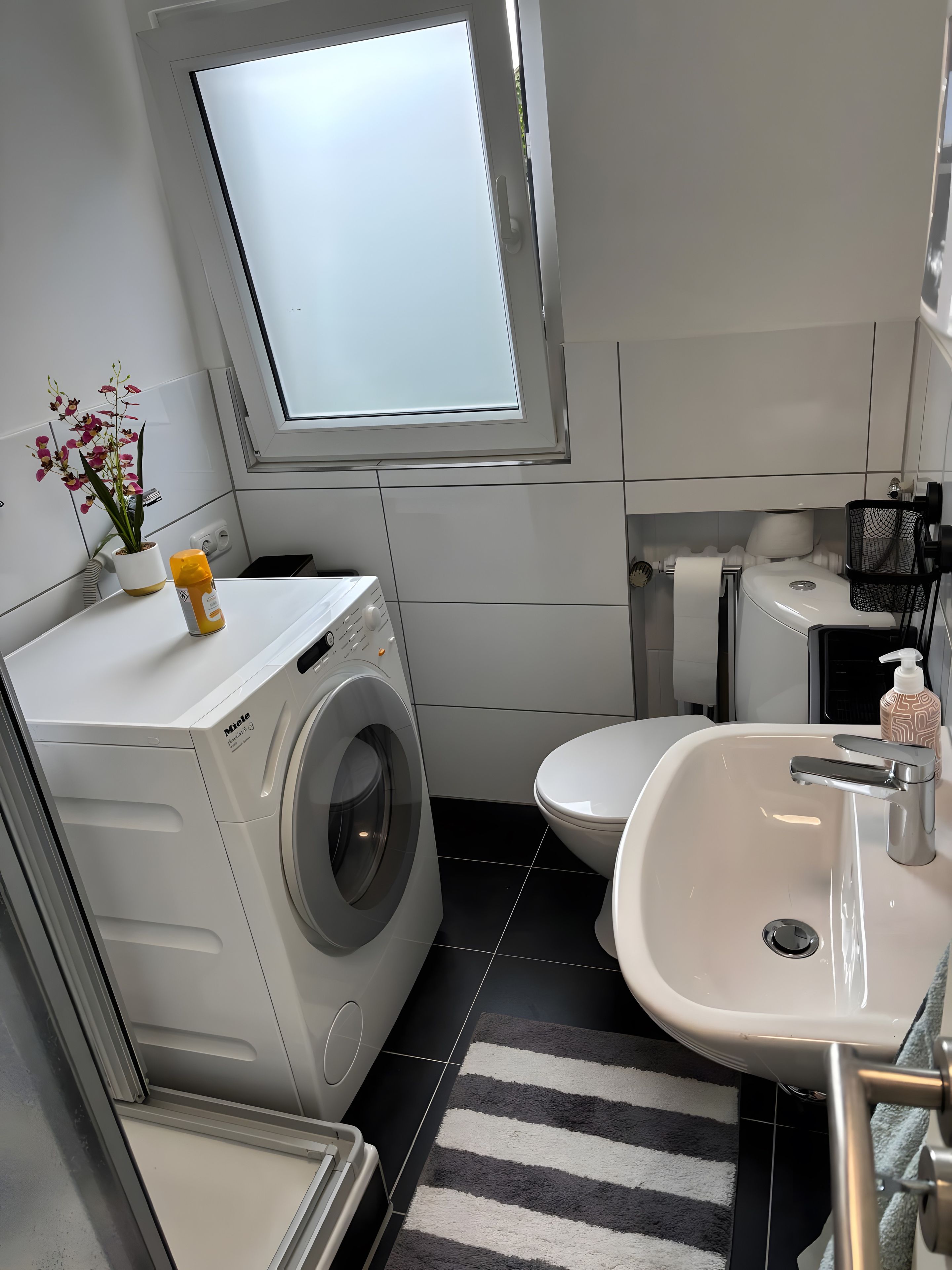 Ein kleines Badezimmer mit Waschmaschine, Toilette und Waschbecken.