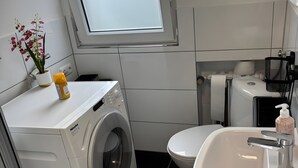 Ein kleines Badezimmer mit Waschmaschine, Toilette und Waschbecken.