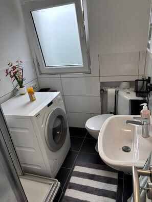 Ein kleines Badezimmer mit Waschmaschine, Toilette und Waschbecken.