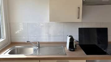 A modern kitchen with a stainless steel sink, a black induction cooktop, and a built-in oven.