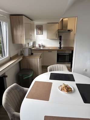 Cocina compacta con área de comedor, que incluye un lavamanos, estufa y sillas.
