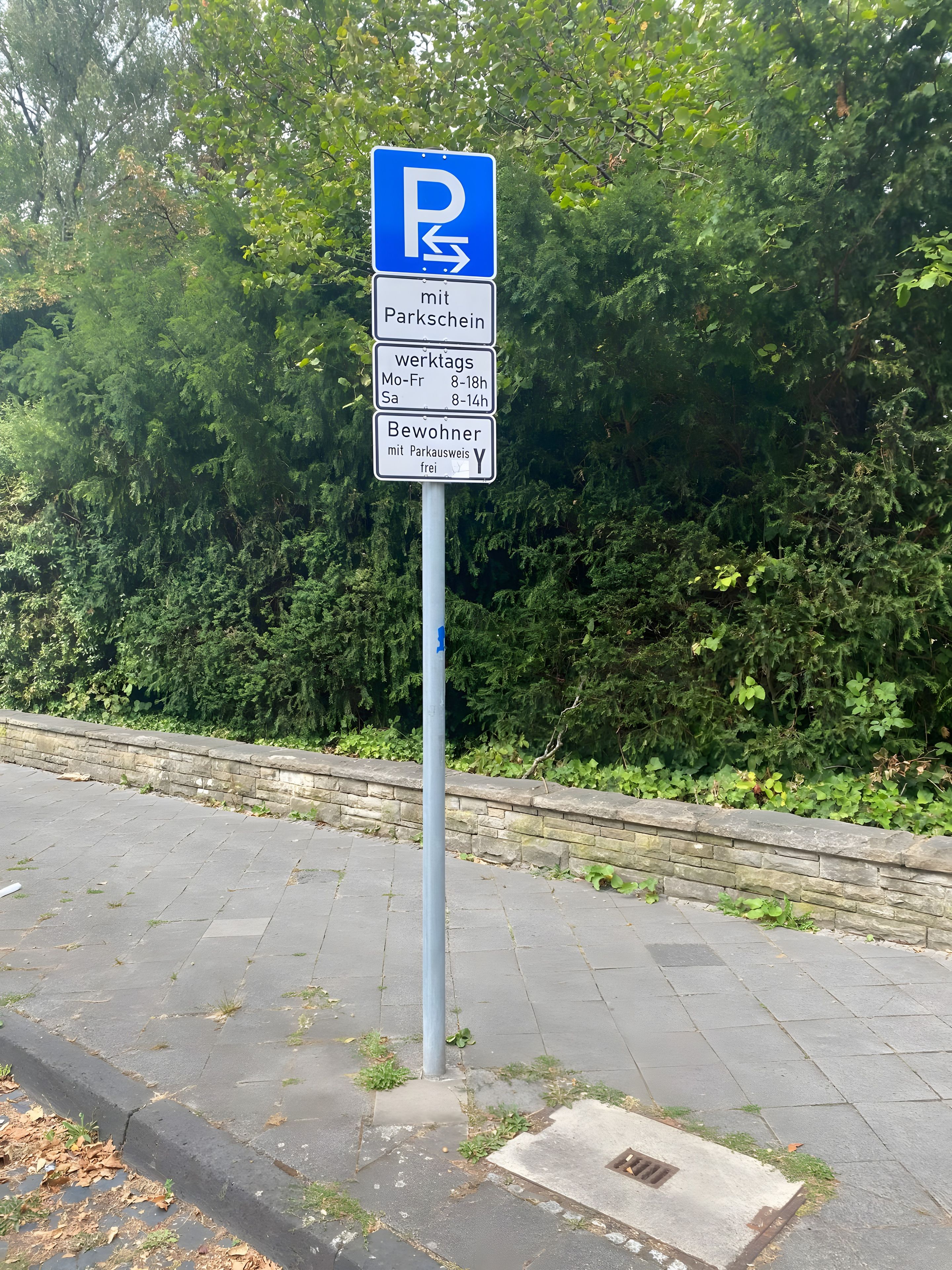 Ein Parkschild mit Pfeilen und Öffnungszeiten.