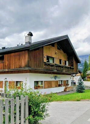 Ein traditionelles Chalet mit Holzfassade, einem Balkon mit Lichterketten und Blick auf die Berge.