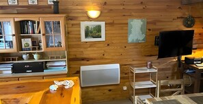 A wooden interior with a cabinet, a framed picture, a radiator, and a television.