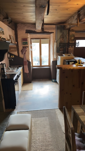 A cozy kitchen with wooden cabinets, a dining table, and a view through a window.