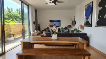 Een moderne woonkamer met een houten salontafel, een blauwe bank en een plafondventilator.