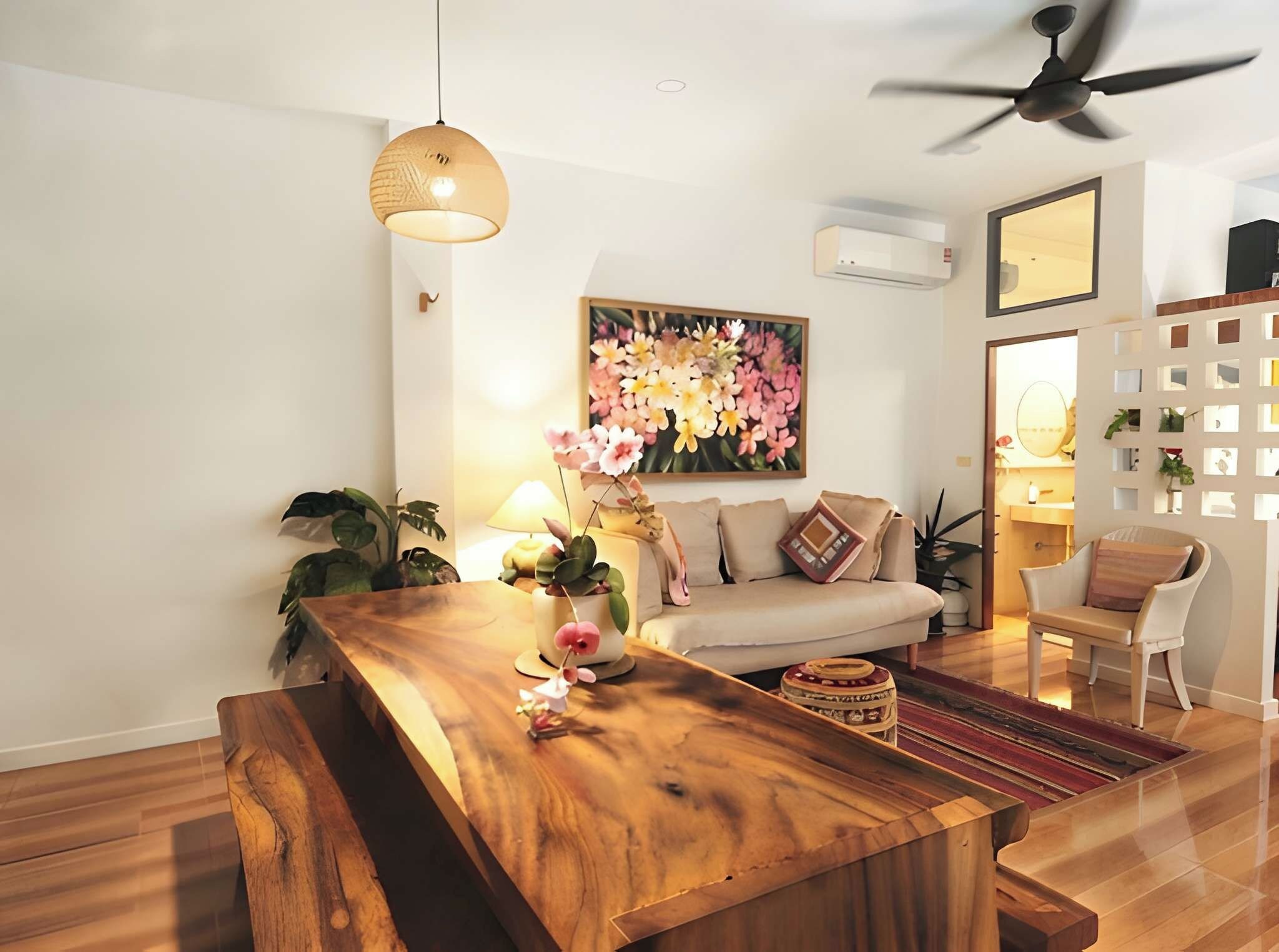 A modern living room with a wooden dining table, a sofa, and a ceiling fan.