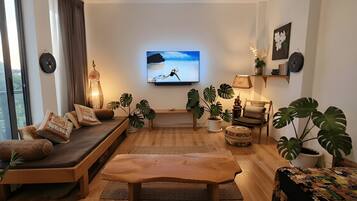Een moderne woonkamer met een bank, salontafel en potplanten.