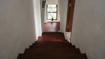 A wooden staircase leading to a room with a window and a vase on the sill.