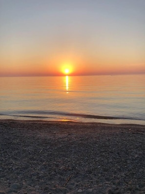 A beach with a sunset over the water.