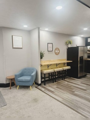 A modern kitchen with a built-in refrigerator, a blue armchair, and a wooden bench with stools.