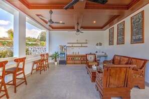 Une pièce spacieuse, dotée de meubles en bois, d’un ventilateur de plafond, d’un réfrigérateur et offrant une vue sur l’extérieur.