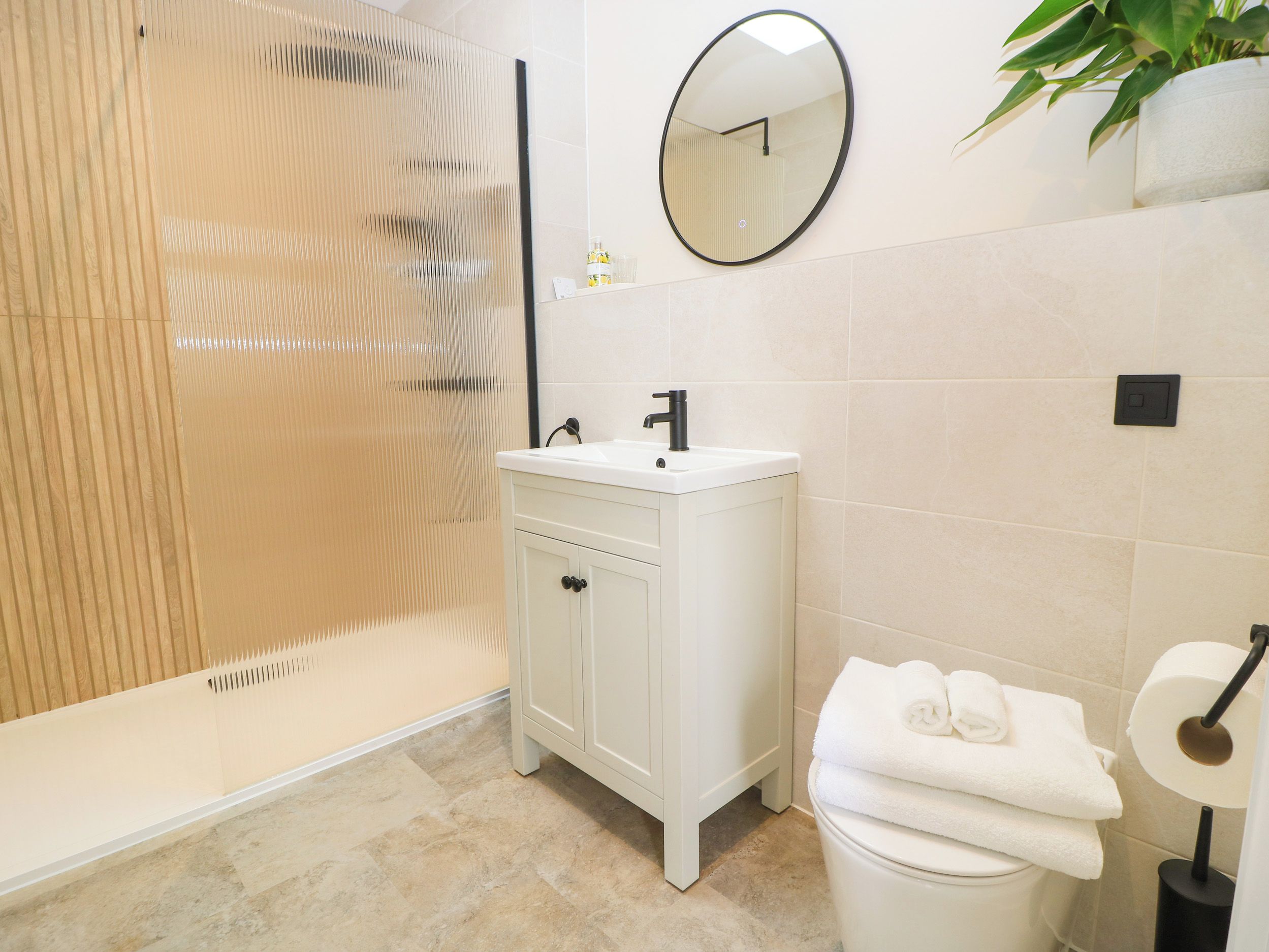 A bathroom with a shower, sink, toilet, and a mirror.