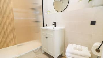A bathroom with a shower, sink, toilet, and a mirror.