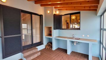Un baño con lavamanos, espejo y ventana con contraventanas.