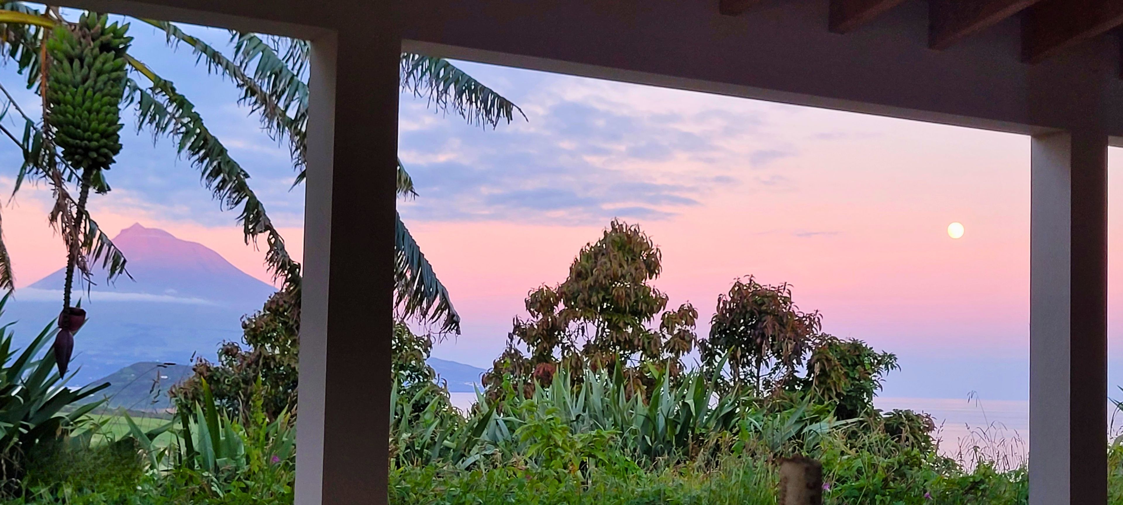 A room with a view of a mountain and the sky at dusk.