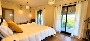 A hotel room with a large bed, two bedside tables, a chair, and a view through the windows.