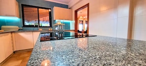 Una cocina moderna con encimeras de granito, electrodomésticos de acero inoxidable y un ventanal grande.