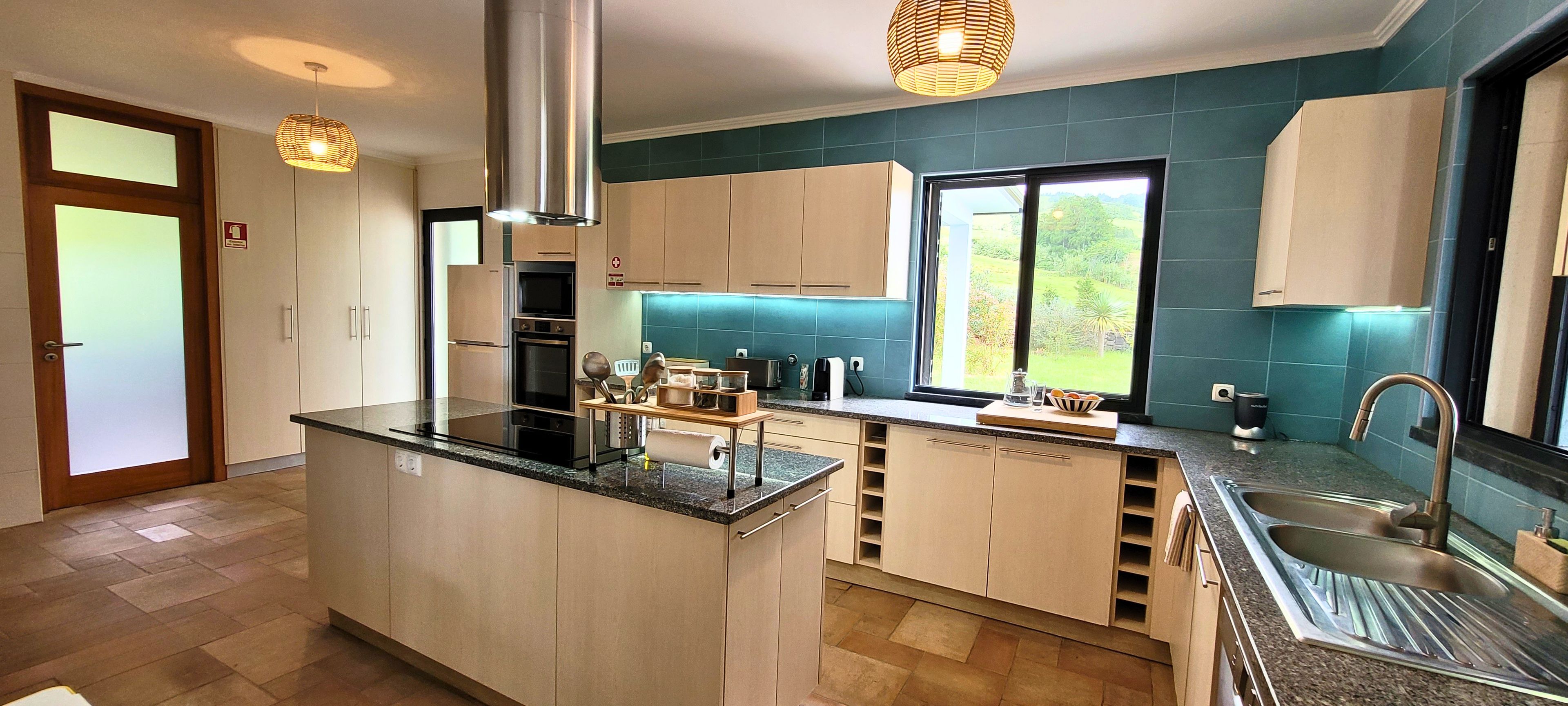 Una cocina moderna con una isla central, electrodomésticos de acero inoxidable y vistas a zonas verdes.