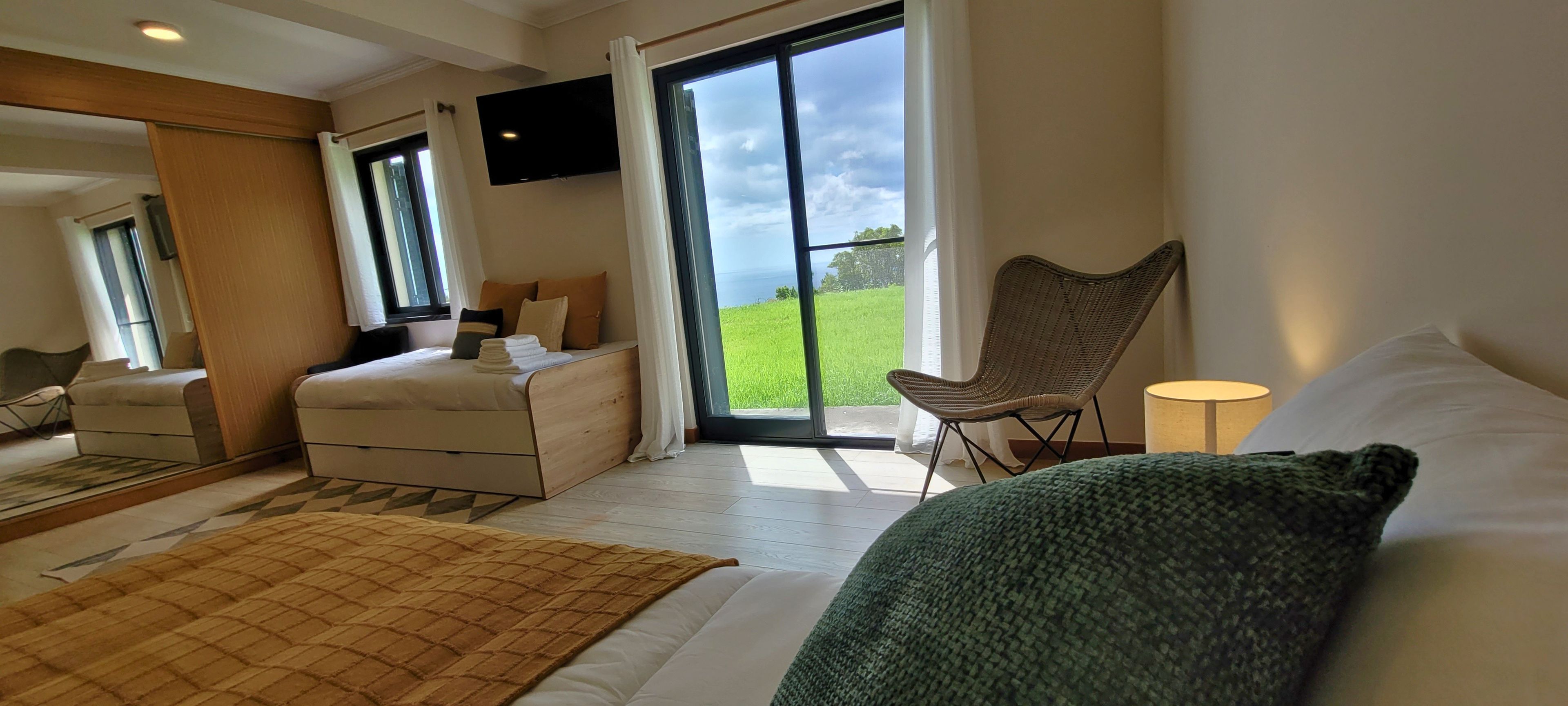 Habitación de hotel con una cama, una silla, un escritorio, un televisor y un ventanal con vistas al exterior.