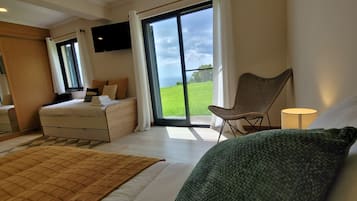 Habitación de hotel con una cama, una silla, un escritorio, un televisor y un ventanal con vistas al exterior.