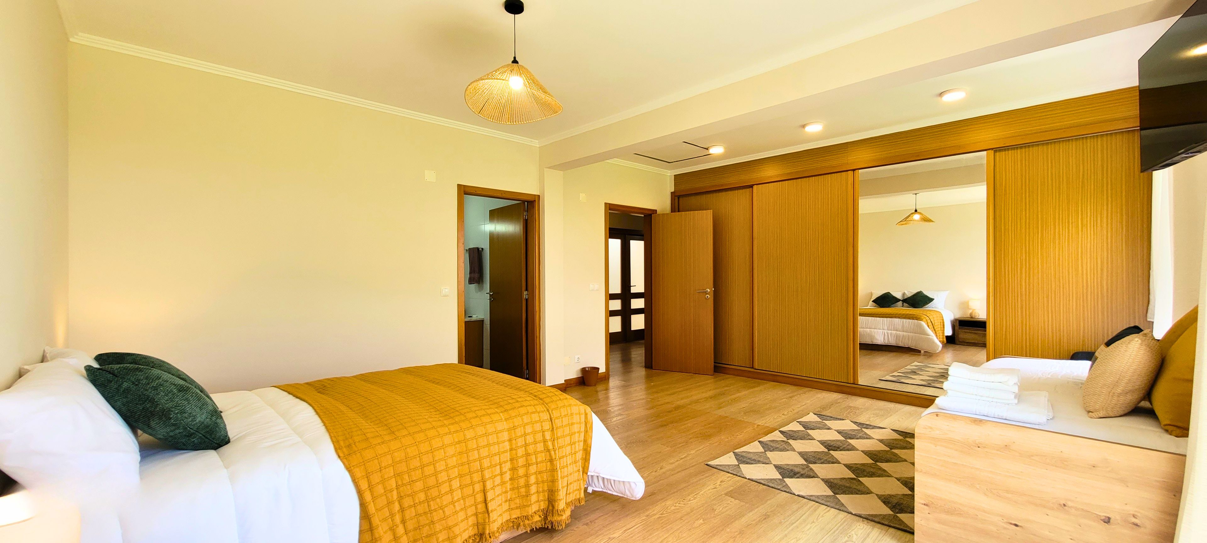 Una habitación de hotel con una cama, una mesita de noche, un espejo y un armario.