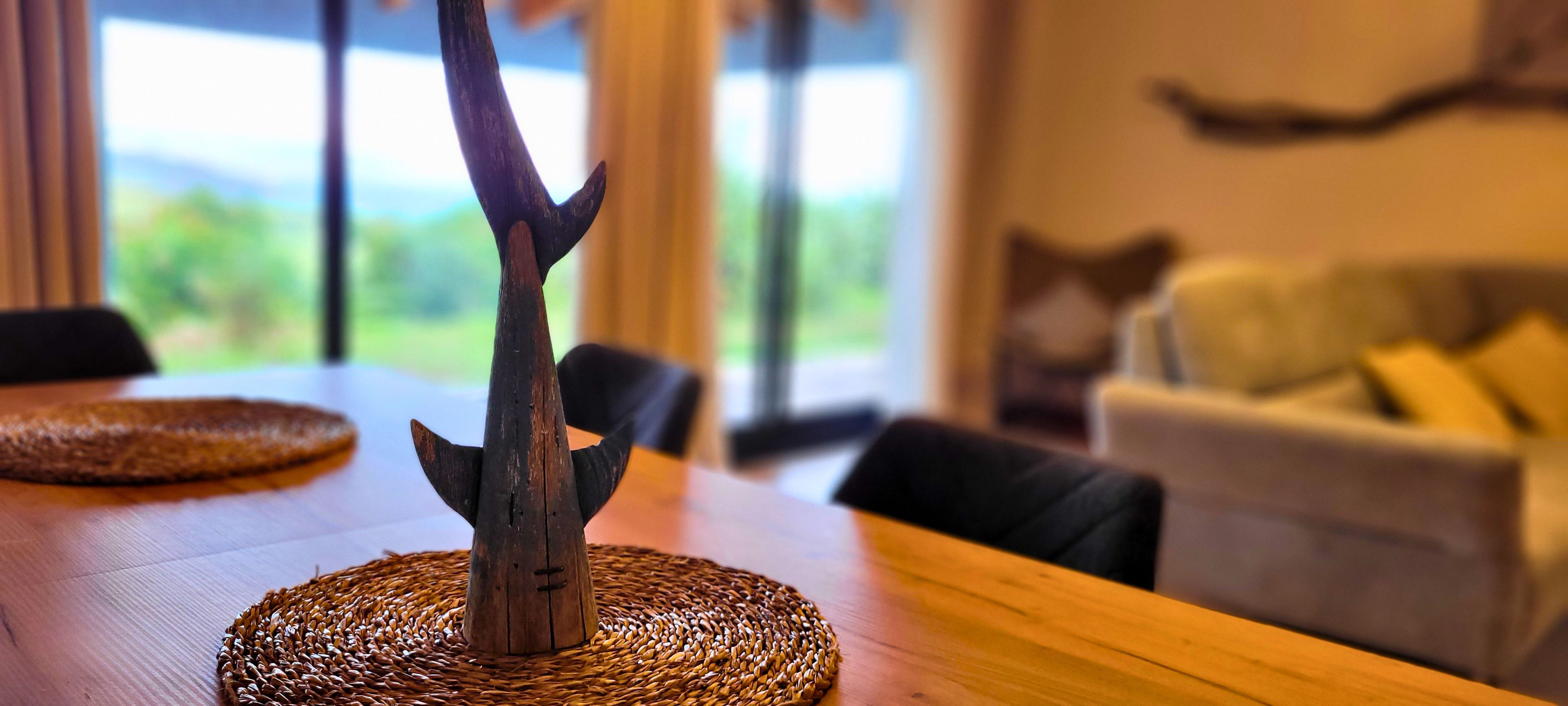 Una mesa de madera con un mantel tejido y un adorno metálico.