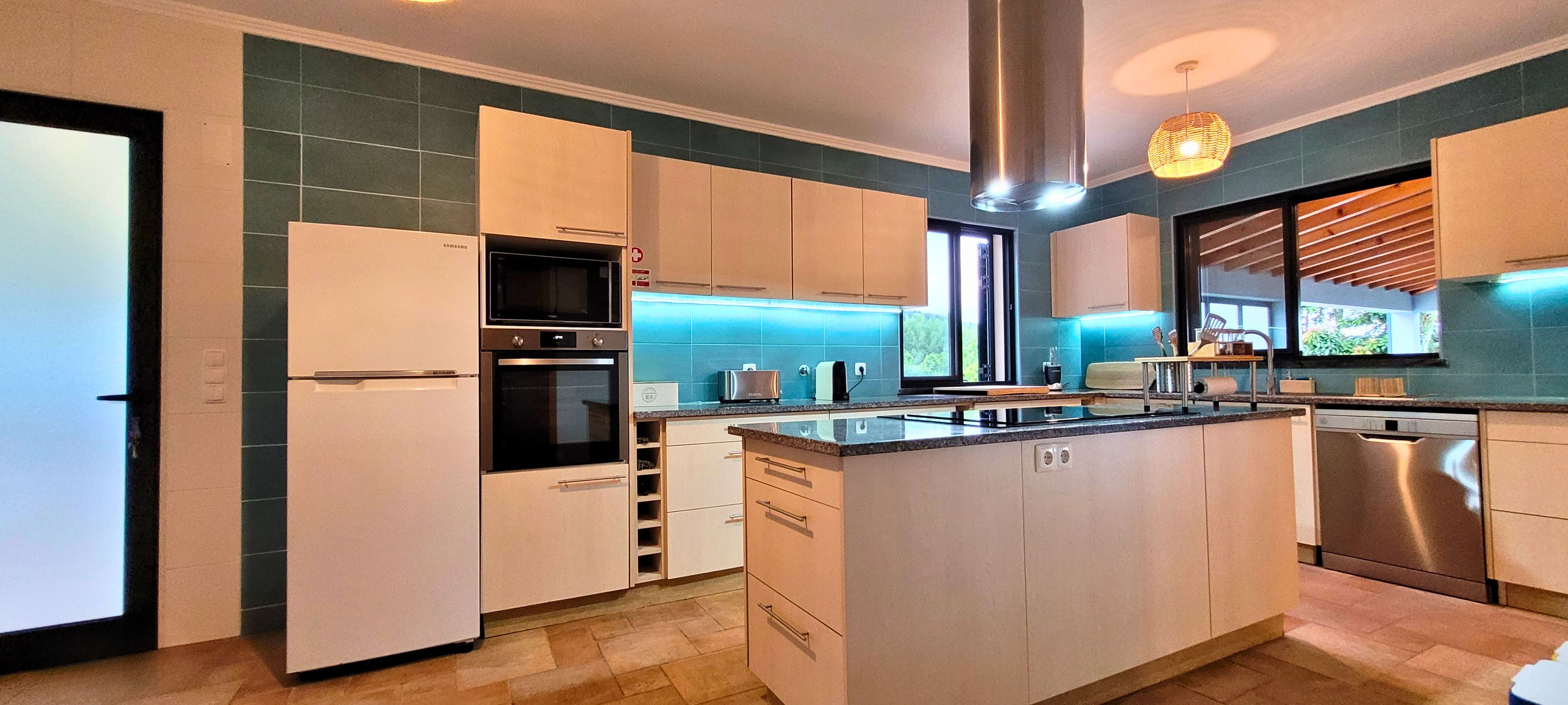 Cocina moderna con isla central, electrodomésticos integrados y vistas al exterior.