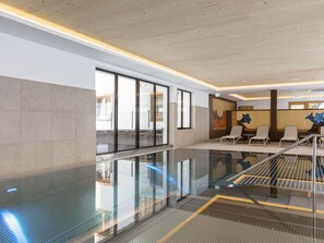 A modern indoor pool area with glass railings, seating, and a view of the outside. - Studio for 2 People (Mittersill)