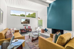 A modern living room with a fireplace, comfortable seating, and artwork on the walls. - Janet’s Hideaway — Classic 1961 Alexander with Private Pool & Spa (Palm Springs)