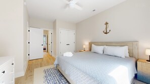 Ein Schlafzimmer mit einem Bett, Nachttischen, einem Deckenventilator und einer Wanddekoration, die wie ein Anker aussieht.