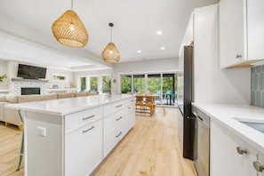 A modern kitchen with white cabinetry, a large island, and pendant lighting. - Private Pickleball Court - Year-Round Combo Pool and Hot Tub - Beach Access (South Haven)