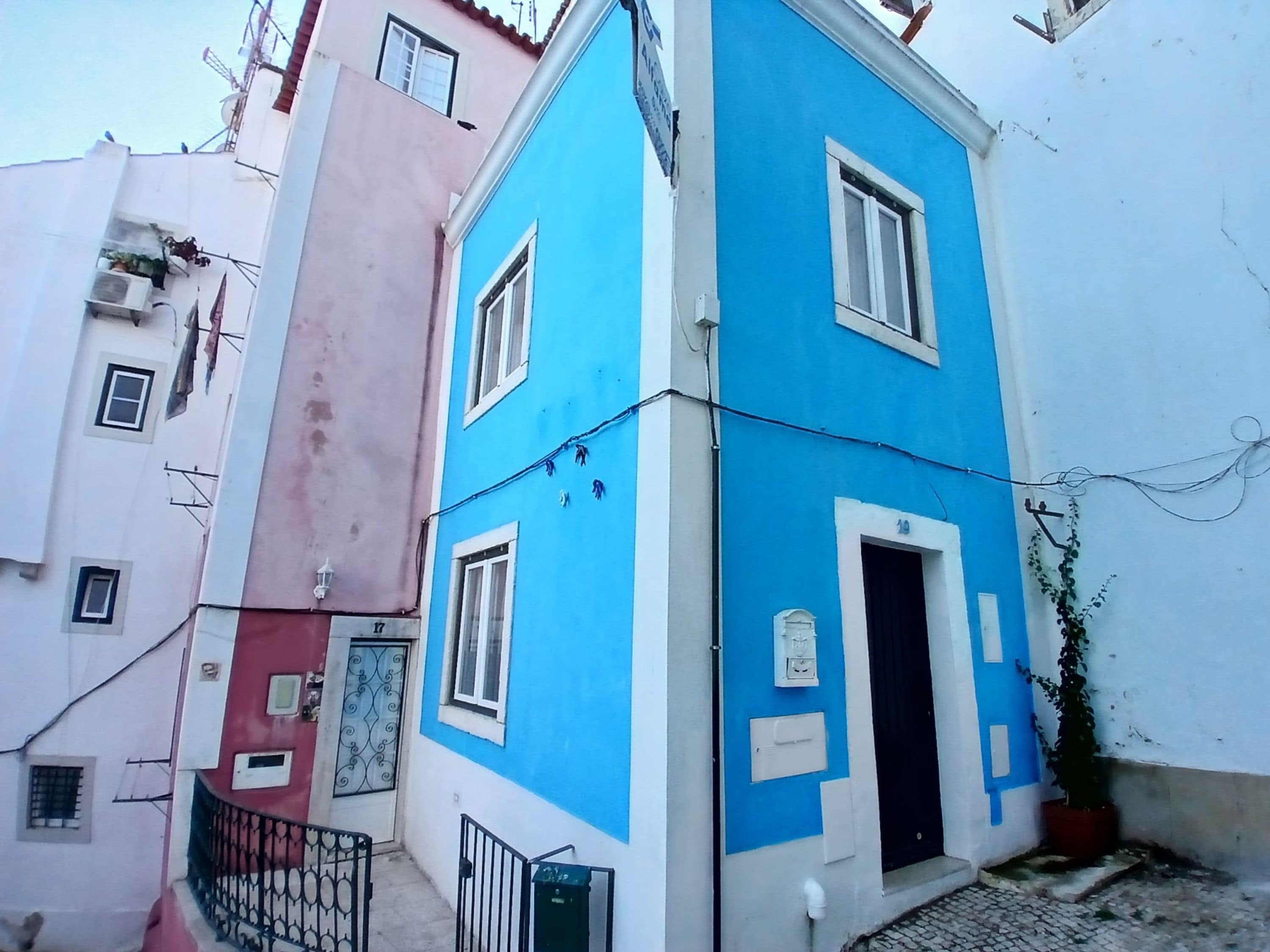 A corner building with a blue facade, a visible door, and a small balcony with a metal railing.