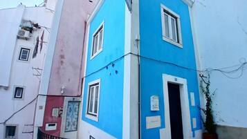 A corner building with a blue facade, a visible door, and a small balcony with a metal railing.