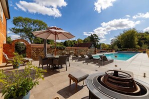 An outdoor pool area with lounge chairs, a table, and a fire pit. - Country House With Pool Cinema Tennis Court (Bury St Edmunds)