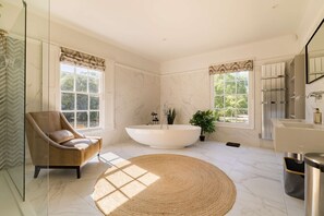 A spacious bathroom with a freestanding bathtub, a modern vanity, and a large window providing natural light. - Country House With Pool Cinema Tennis Court (Bury St Edmunds)