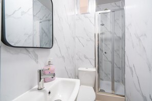 A bathroom with a white sink, a mirror, and a glass shower enclosure. - Perfect Booking 4-bed Group Home in Sheffield (Sheffield)