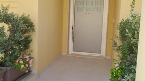 Ein Korridor mit einer Tür, auf der 'SMIRALDIA TOP ROOMS' steht, der zu einem Zimmer führt.