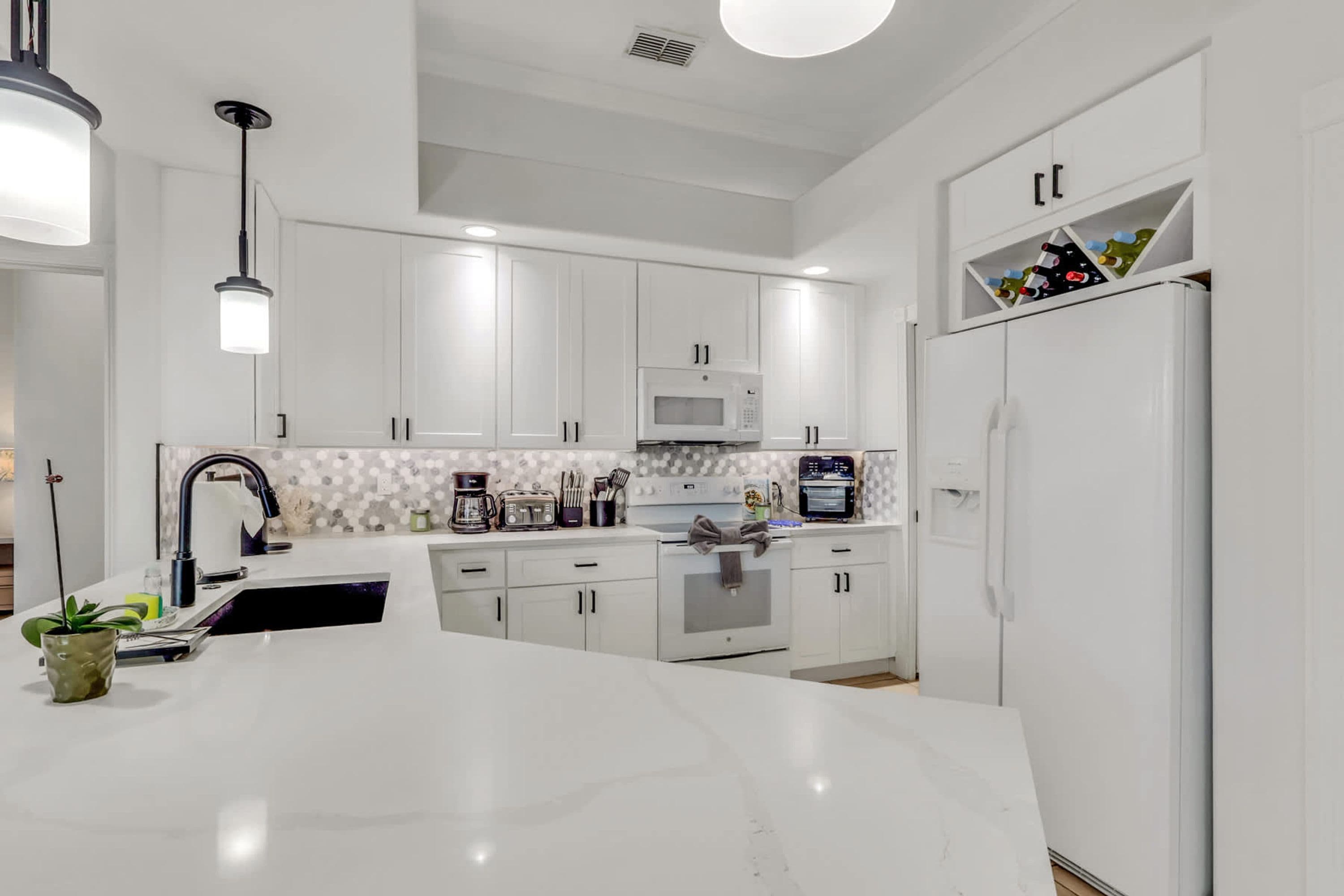 A modern kitchen with white cabinetry, a central island, and a built-in oven.