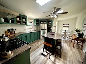 Une cuisine équipée d’une cuisinière à gaz, d’un ventilateur de plafond et d’un plancher en bois.