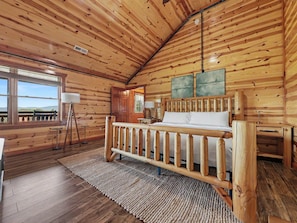 Ein Holzblock-Interieur mit einem Bett, einem Schreibtisch, einem Stuhl und einem Fenster mit Aussicht.