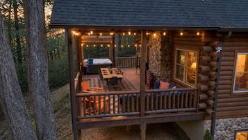 A log cabin with a deck, outdoor seating, and a hot tub.