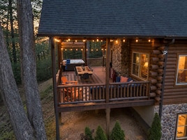 A log cabin with a deck, outdoor seating, and a hot tub.