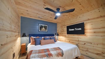 A bedroom with a bed, a ceiling fan, a framed picture, and a 'Home Team' sign.