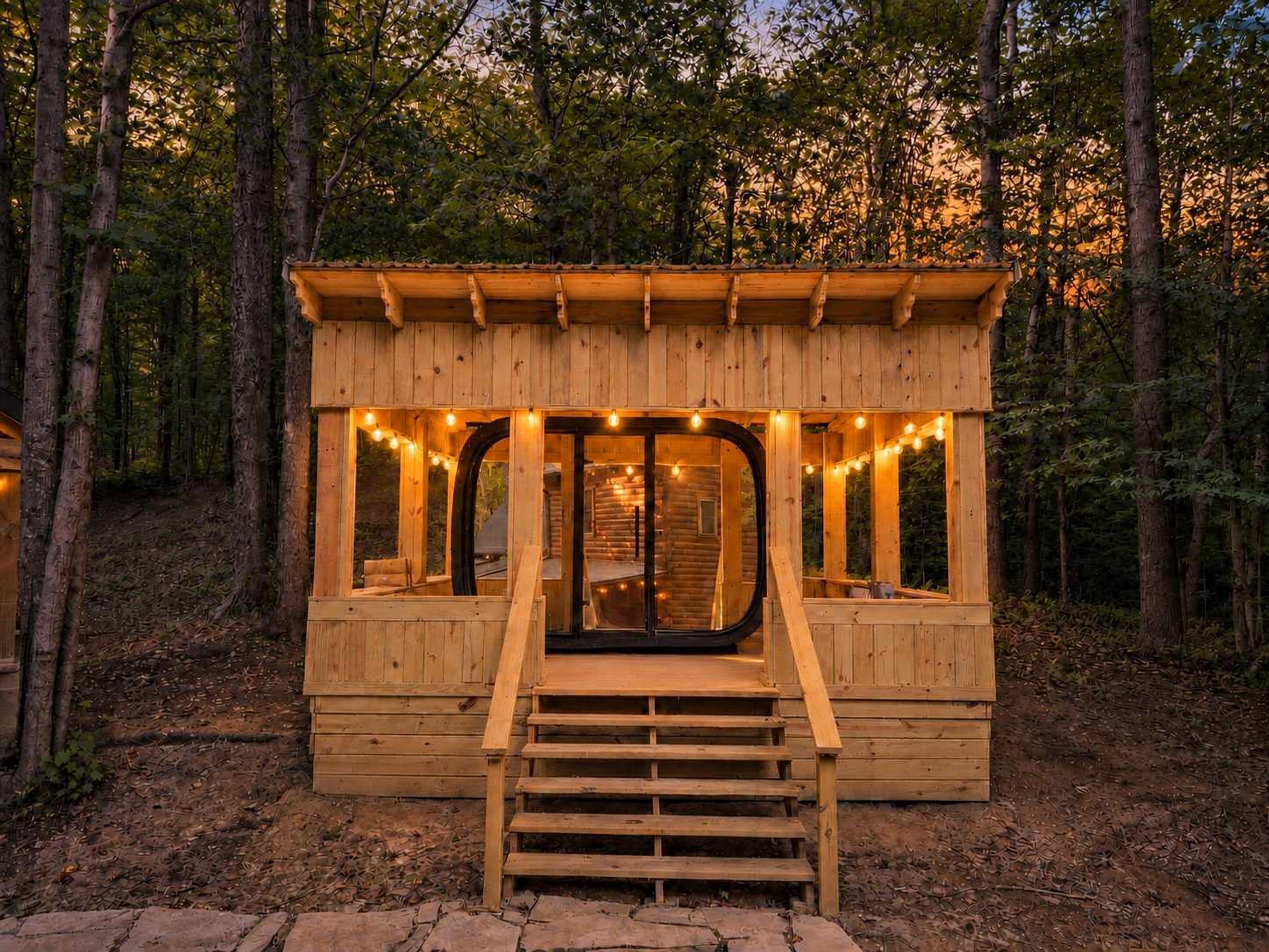 Una cabaña de madera con porche, ventanas y una escalera que lleva a la entrada.