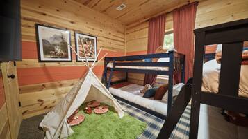 Una habitación acogedora con paredes de madera, una cama litera, un tipi y dos cuadros enmarcados.