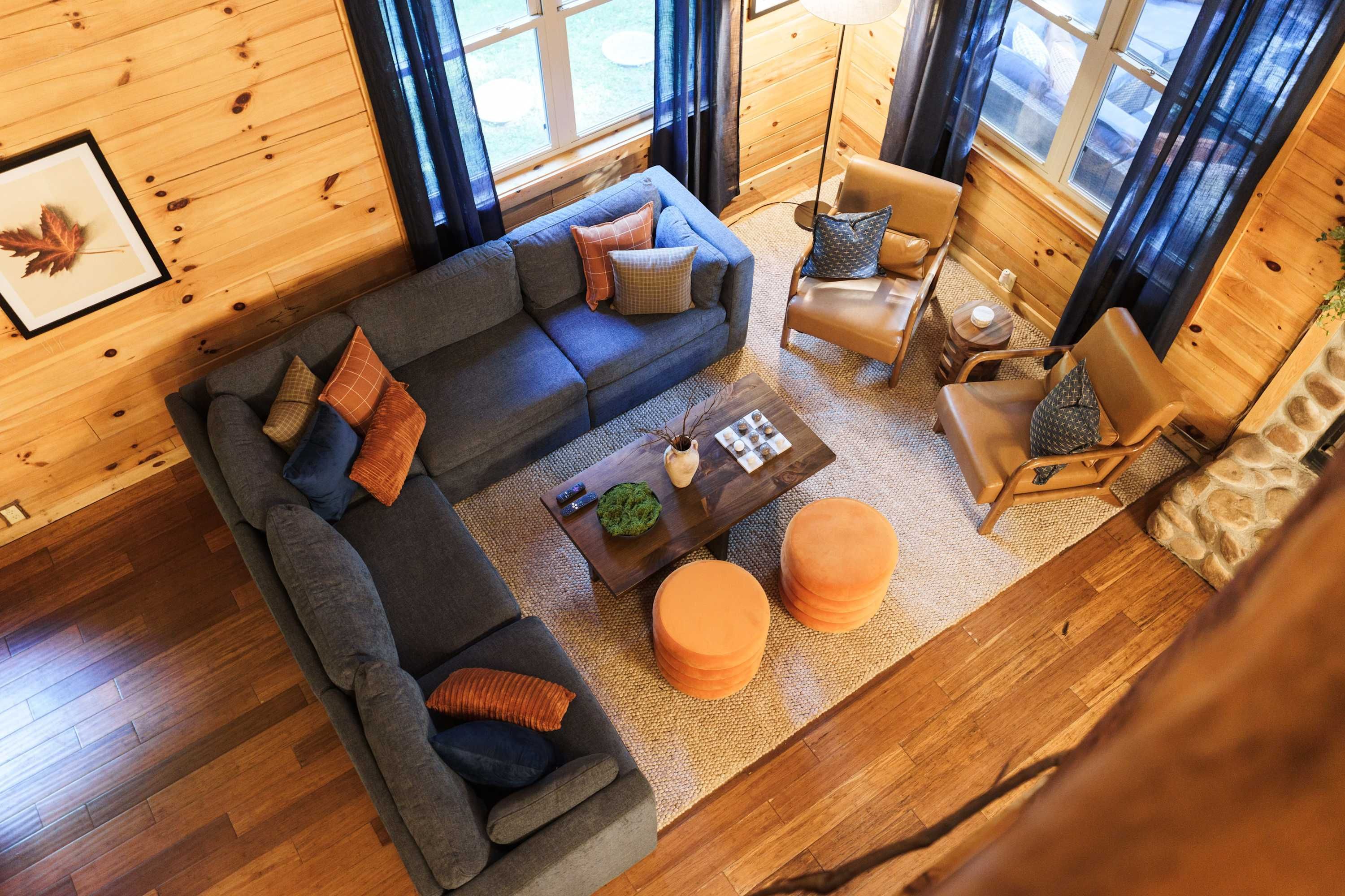 Interior acogedor de una cabaña con un sofá seccional, una mesita redonda y un sillón de cuero.